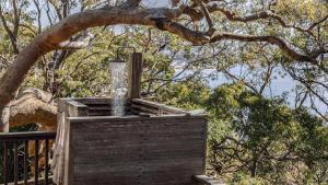 a water fountain in a wooden box under a tree at Coastal Wilderness Retreat in Hardys Bay +15 photos