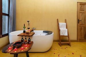 a bathroom with a tub and a table with bottles of wine at Buffalo Safari Lodge in Katunguru