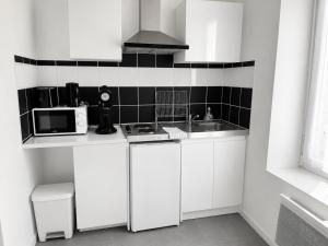 a white kitchen with a sink and a microwave at violette 3 in La Souterraine