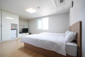 a white bedroom with a bed and a television at 프레지던트 신라연수원 in Gyeongju +19 photos
