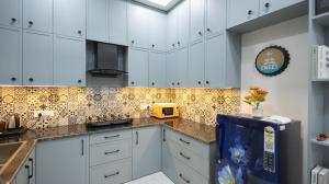 a kitchen with white cabinets and a blue refrigerator at The Afternoon Stays in Mohali