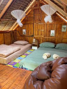 two beds in a room with wooden walls at Khao Phang Camping in Ban Pha Saeng Lang