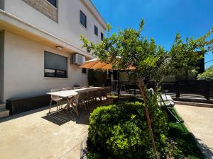 a patio with a table and chairs and an umbrella at Zimmer Monte in Dāliyat el Karmil