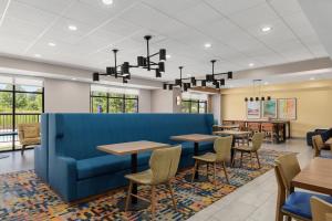 a restaurant with tables and chairs and a blue couch at Hampton Inn Farmville in Farmville