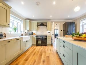 a kitchen with white cabinets and a wooden floor at Scarrow Beck House in Hanworth