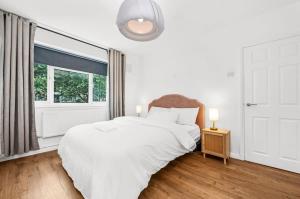 a white bedroom with a large bed and a window at Spacious London Bridge Flat in London