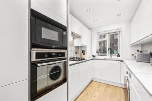 a kitchen with white cabinets and a washer and dryer at Spacious London Bridge Flat in London