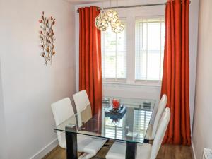 a dining room with a glass table and white chairs at Serenity in Cellardyke