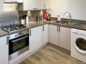 a kitchen with a stove and a sink and a washing machine at Serenity in Cellardyke