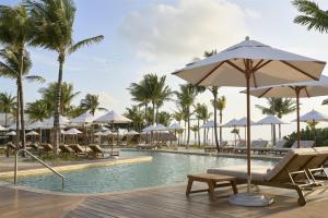 a resort pool with chairs and umbrellas and palm trees at Alila Mayakoba by Hyatt in Playa del Carmen