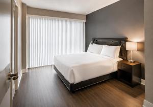 a bedroom with a white bed and a large window at Oak Crown Suites in Toronto