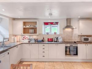 a kitchen with white cabinets and a stove top oven at Windy Ridge Low Row in Feetham