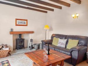 a living room with a leather couch and a wood stove at Windy Ridge Low Row in Feetham