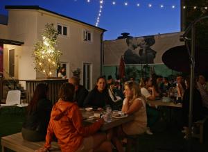 a group of people sitting at tables in a yard at Rosalma Hostel in Porto