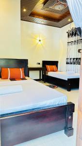 a bedroom with two beds with orange pillows and a table at Yala Zafiro in Kataragama