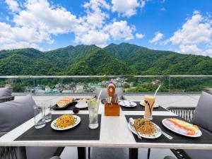 a table with plates of food on a balcony with mountains at Hotel Weekend Heights in Rishīkesh