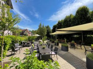 a patio with tables and chairs and umbrellas at Hotel am Kloster in Werne an der Lippe