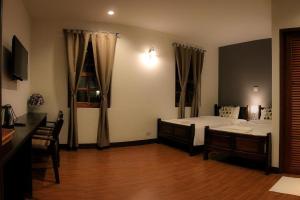 a bedroom with two beds and a wooden floor at Phumin Place Hotel in Nan