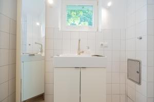 a white bathroom with a sink and a window at Stabenweg Whg. 1 in Göhren
