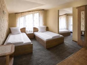 a bedroom with two beds and two windows at Pensiunea Mirela Bears Cave in Chişcău