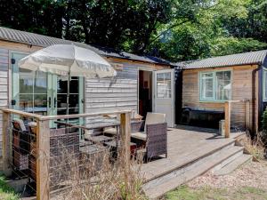 a wooden deck with a table and an umbrella at Hoy Haven in Whitwell