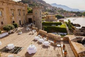a patio with white tables and chairs and a building at La casetta in Trabia