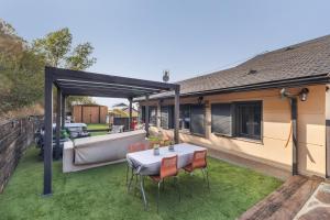 a patio with a table and chairs on the grass at Villa Ana Esperanza - El Espinar in El Espinar