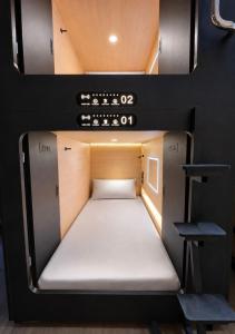 a small bed in the back of a small room at OWNLY CAPSULE Hotel in Bangkok