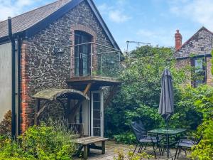 a patio with a table and an umbrella at Coach House in Holsworthy
