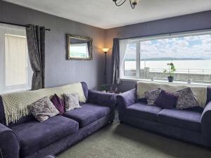 a living room with two purple couches and a window at Mo Dhachaidh in Gairloch