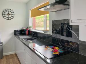 a kitchen with a counter with a clock on the wall at Mo Dhachaidh in Gairloch