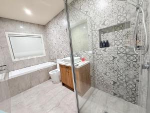 a bathroom with a shower and a toilet and a sink at Serenity Suite with Private Bathroom in Wyndham Vale +8 photos