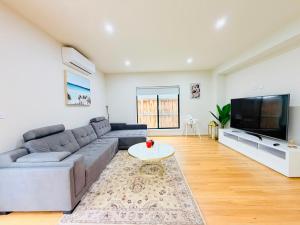 a living room with a couch and a tv at Serenity Suite with Private Bathroom in Wyndham Vale