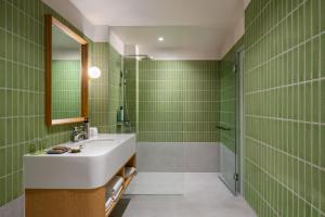 a bathroom with green tiled walls and a sink at Anantasila Beach Resort Hua Hin in Hua Hin