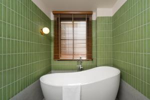 a green tiled bathroom with a tub and a window at Anantasila Beach Resort Hua Hin in Hua Hin