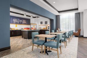 a waiting room with tables and chairs and a kitchen at Hampton Inn & Suites Memphis Germantown in Memphis