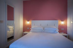 a bedroom with a large white bed with red walls at Arli Hotel Hideaway Punta Ala - Adults Only in Punta Ala