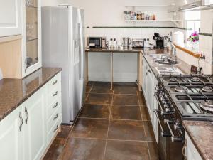 a kitchen with white cabinets and a tile floor at Weaver's Cottage in Banchory