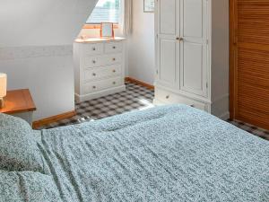 a bedroom with a blue bed and a dresser at Weaver's Cottage in Banchory +7 photos