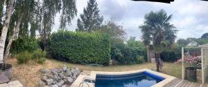 a swimming pool in a yard with trees and bushes at BAAN THAI ST MALO in Saint Malo