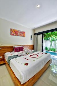 a bedroom with a large bed with red flowers on it at Bali Corail Villas in Kerobokan