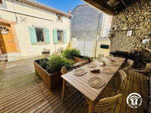 a wooden deck with a table and chairs at Le carpe diem in Pomas