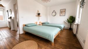 two beds in a room with wood floors at Maison Luma in Basse-Yutz