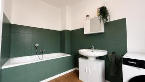 a green bathroom with a sink and a bath tub at Maison Luma in Basse-Yutz