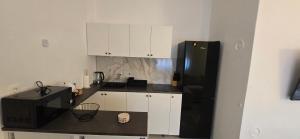 a kitchen with a black refrigerator and white cabinets at Apartman-Zara m in Zadar