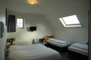 a bedroom with two beds and a tv and a window at Duinoord Oostkapelle in Oostkapelle