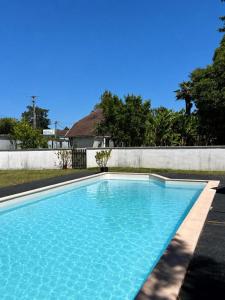 a large blue swimming pool in front of a wall at Maison le baron in Bélus