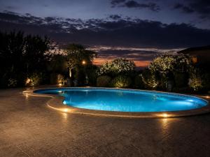 a swimming pool with lights in a yard at night at Madona Casas in Psilá Alónia