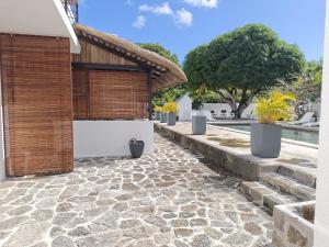 a patio with a stone walkway next to a pool at Résidences Le Beau Manguier in Pereybere