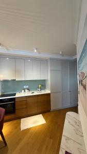 a kitchen with white cabinets and a wooden floor at Perla Petrus in Rafailovici